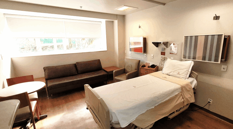 Sala de internação da Perinatal, com uma cama, janela ampla e um sofá de acompanhante