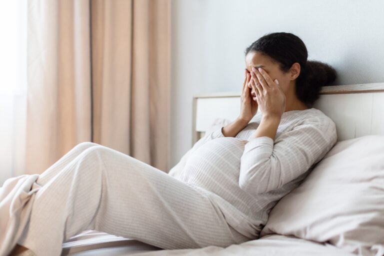 Pregnant,Black,Woman,Lying,In,Bed,Covering,Face,With,Hands,